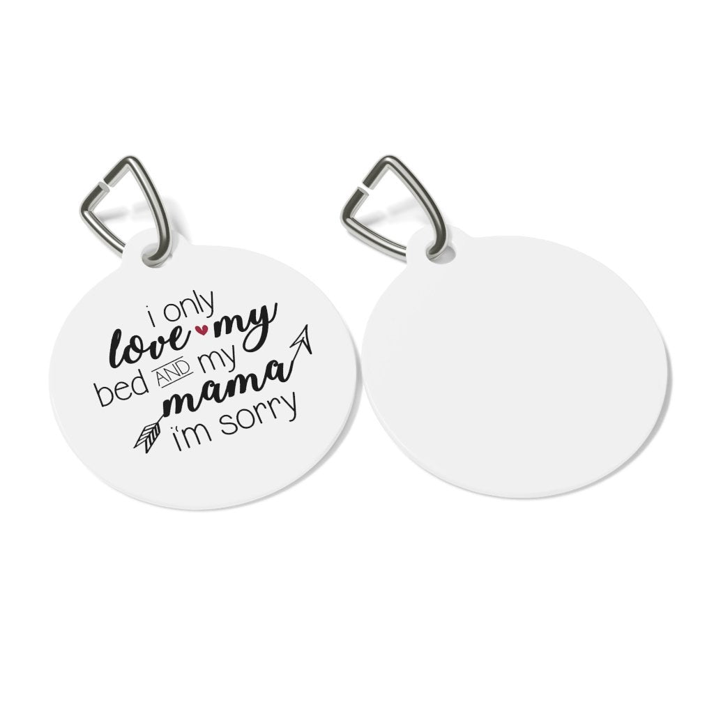 A white coated solid metal pet tag with the text 'I only love my bed and mama, I'm sorry' printed on it, attached to a metal clip.
